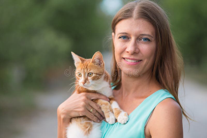 Woman holding a cat in her arms and hugging outdoors
