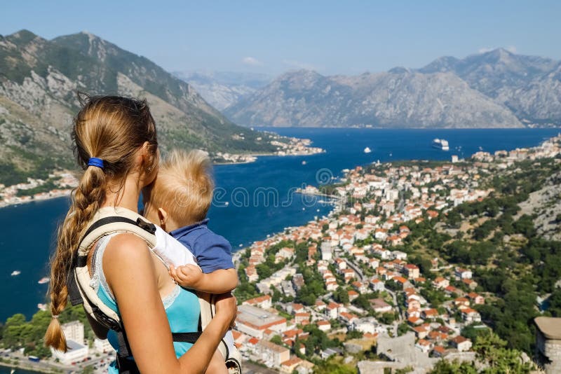 Woman holding child and looking at the mountains and the Bay of Kotor in Montenegro at the top of the mountain. Rear view. royalty free stock image Woman holding child and looking at the mountains and the Bay of Kotor in Montenegro at the top of the mountain. Rear view. royalty free stock image