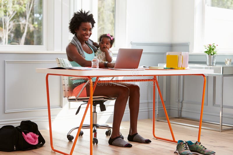 Woman holding child using computer at home after exercising stock photo Woman holding child using computer at home after exercising stock photo