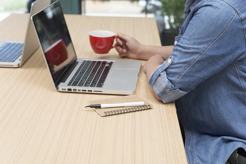 woman holding coffee cup with laptop computer, notebook and pen for use as working concept