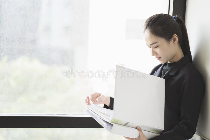 Woman holding document files beside a window