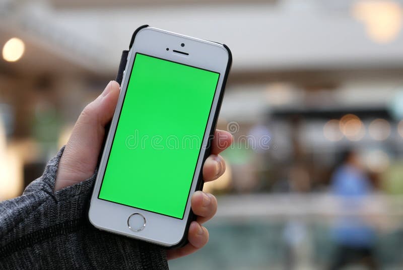 Woman holding green screen phone with blur people having dinner stock photo Woman holding green screen phone with blur people having dinner stock photo