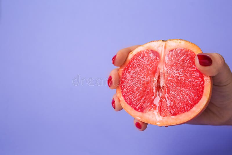 Woman holding half of juicy grapefruit on color background. Erotic concept stock photography Woman holding half of juicy grapefruit on color background. Erotic concept stock photography
