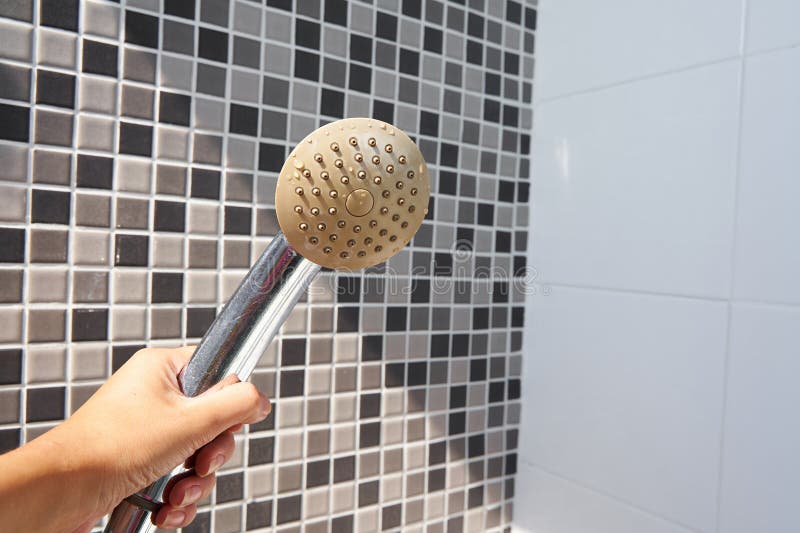 Woman holding in hand corroded limescale calcified old shower head hanging from a stand inside cabin stock photos