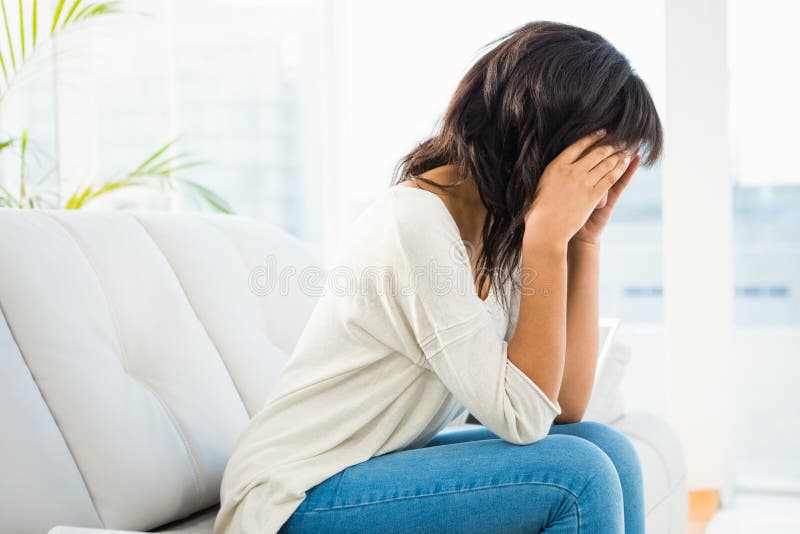 Woman Holding Her Head while Sitting on the Couch Stock Image Image