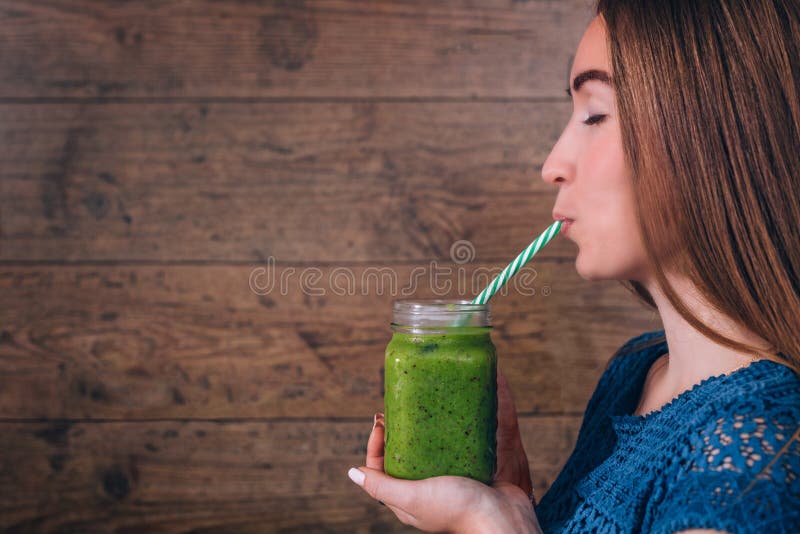 Woman holding kiwi smoothie. Healthy lifestyle concept. Dark wooden background. royalty free stock photos Woman holding kiwi smoothie. Healthy lifestyle concept. Dark wooden background. royalty free stock photos