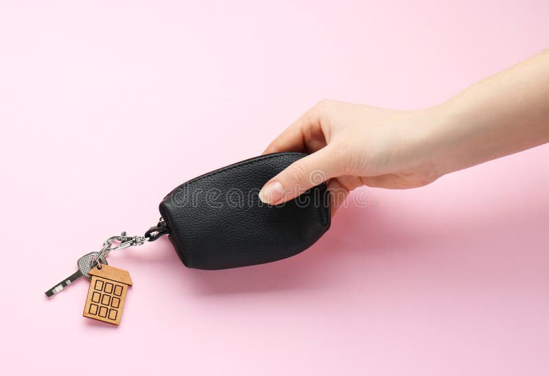 Woman holding leather case with key on pink background. Woman holding leather case with key on pink background