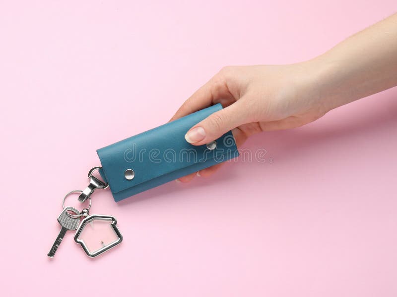 Woman holding leather case with key on pink background. Woman holding leather case with key on pink background