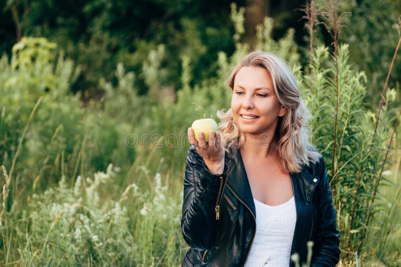 Woman holding and looking at a green Apple while relaxing in the Park royalty free stock photography Woman holding and looking at a green Apple while relaxing in the Park royalty free stock photography
