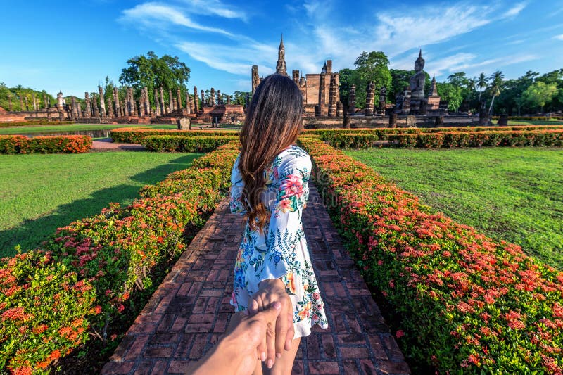 Woman holding man`s hand and leading him to Wat Mahathat Temple in the precinct of Sukhothai Historical Park