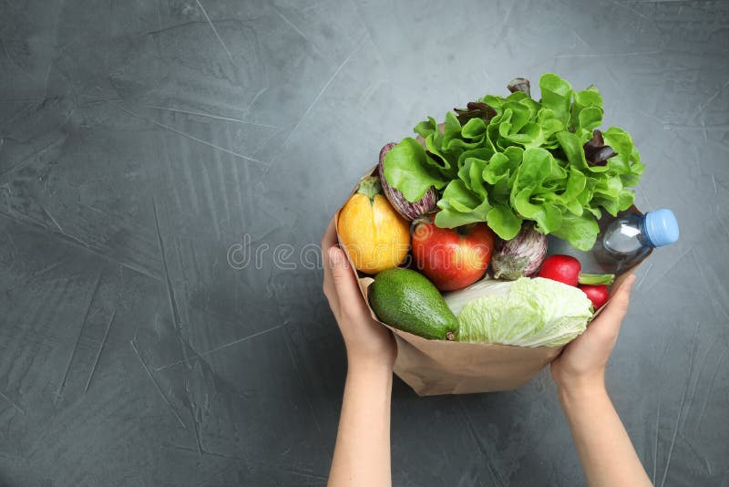 Woman holding paper package full of fresh vegetables and fruits on dark background, top view royalty free stock photos Woman holding paper package full of fresh vegetables and fruits on dark background, top view royalty free stock photos