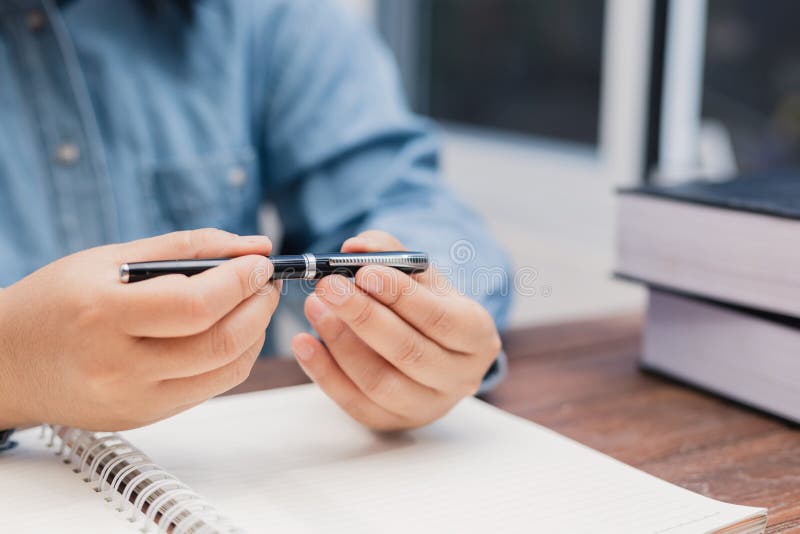 Woman holding a pen sitting on a desk writing royalty free stock photo