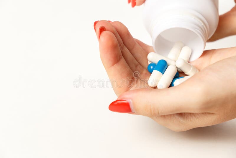 Woman holding pills on hand. Medicine and health care concept. Hand spilling pills for the pain of a bottle on white background
