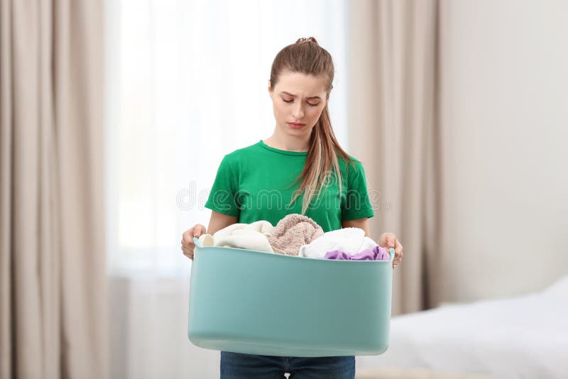 Woman holding plastic basket with dirty laundry