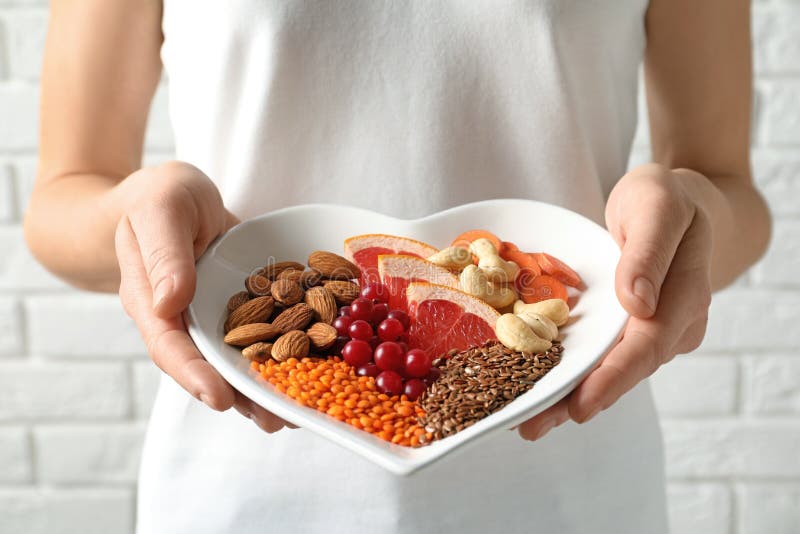 Woman holding plate with products for heart-healthy diet
