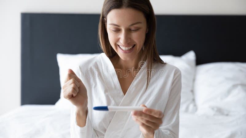 Woman holding pregnancy test focus on excited happy face