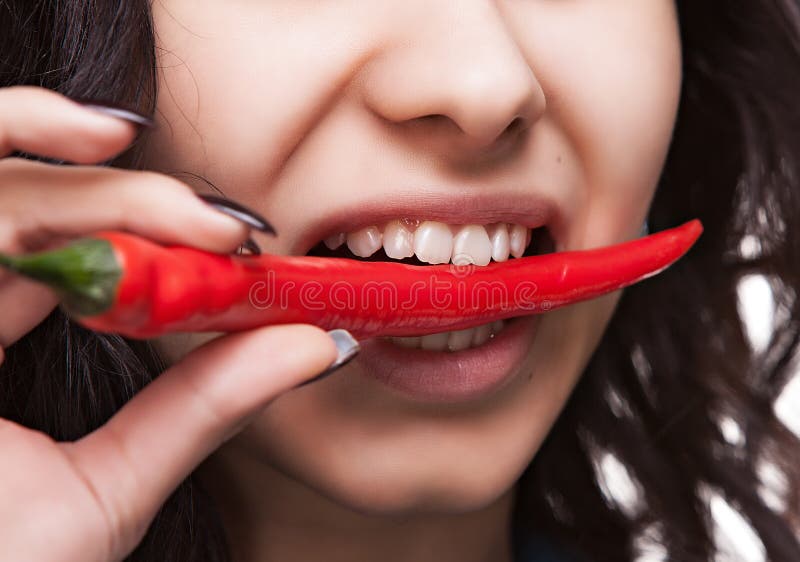 Woman holding red hot chili pepper in mouth