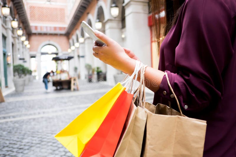 Woman holding shopping bag and using smartphone for shopping online, shopping concept
