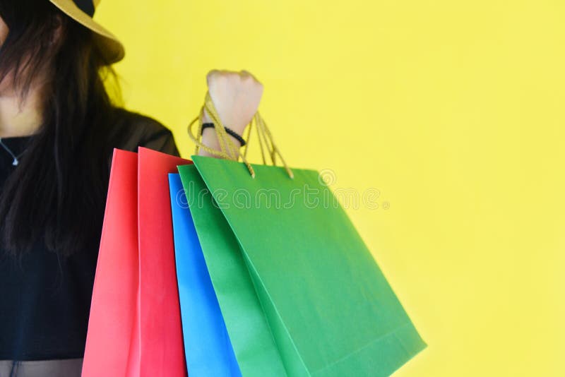 Woman holding shopping bags for girl fashion shopping in the summer colorful yellow stock photo Woman holding shopping bags for girl fashion shopping in the summer colorful yellow stock photo