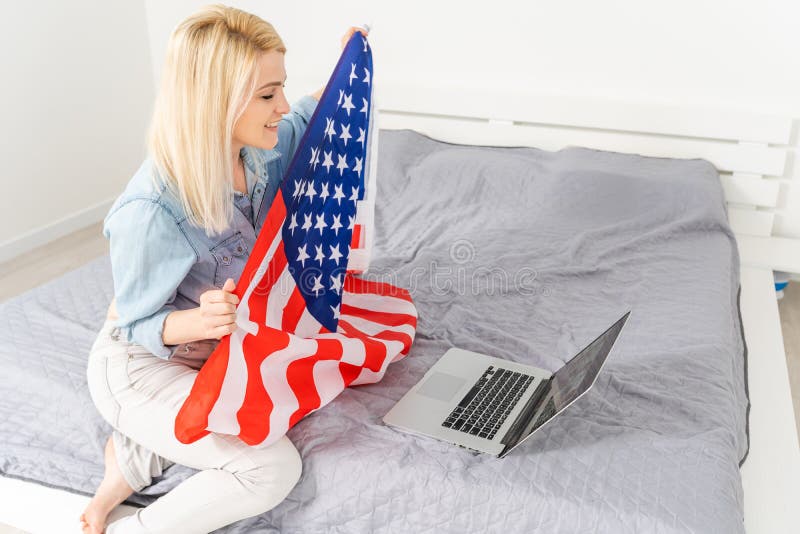 Woman holding usa flag and video by laptop