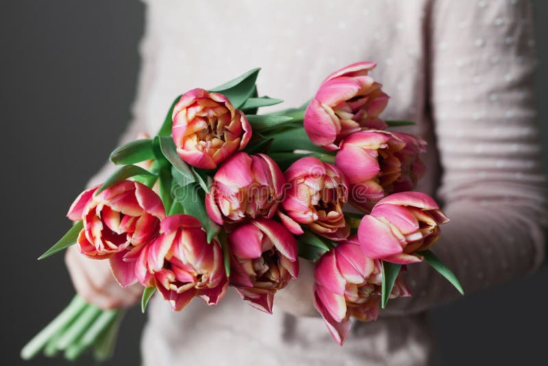Woman holds a bouquet of spring pink tulips flowers. Vintage lifestyle scene with beautiful day light. stock photo Woman holds a bouquet of spring pink tulips flowers. Vintage lifestyle scene with beautiful day light. stock photo