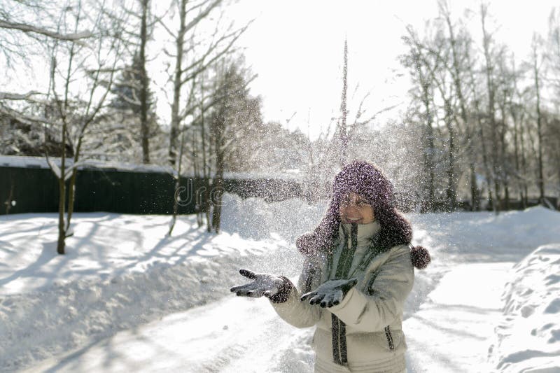 A woman holds a handful of snow in her hands and blows on it. Wi royalty free stock photo A woman holds a handful of snow in her hands and blows on it. Wi royalty free stock photo