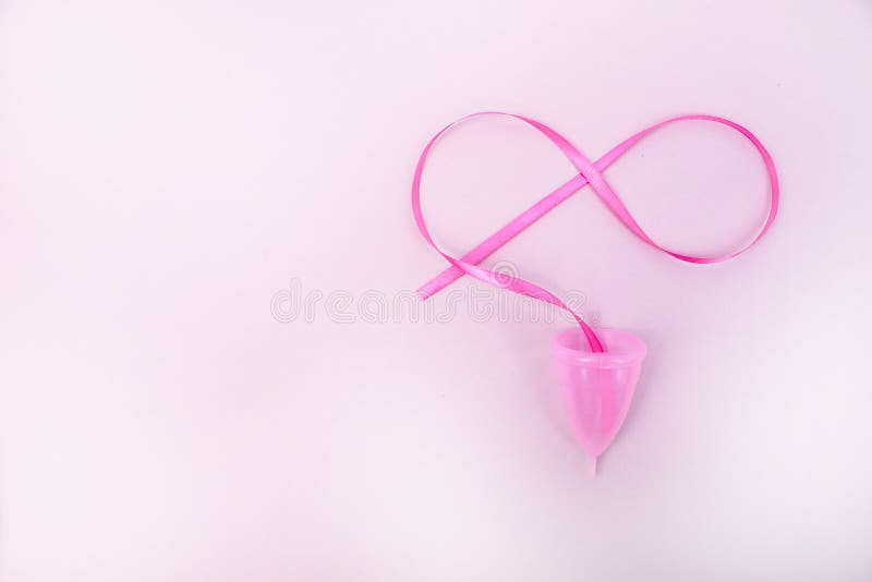 A woman holds a menstrual cup in her hand on a pink background. The concept of women`s health, hygiene, alternatives pads and royalty free stock images A woman holds a menstrual cup in her hand on a pink background. The concept of women`s health, hygiene, alternatives pads and royalty free stock images
