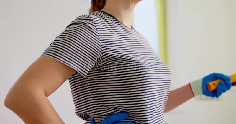 Woman holds a paint roller brush in hand after completing home painting project stock footage