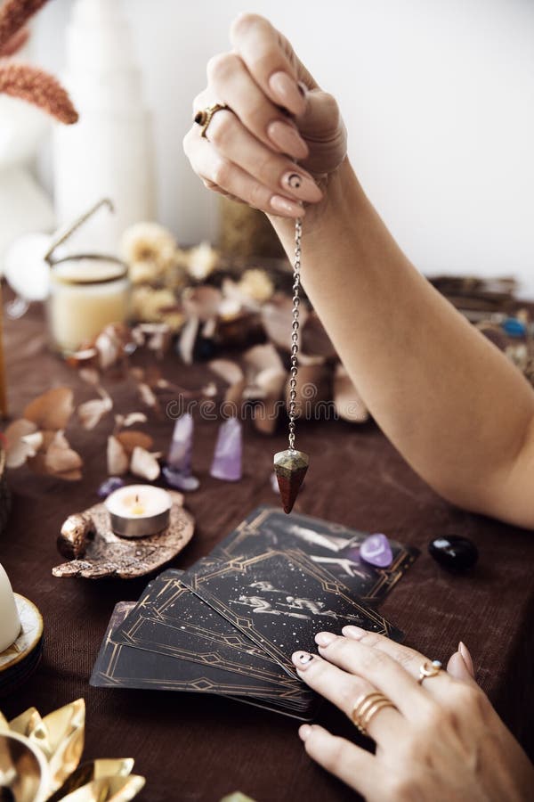 A Woman Holds a Pendulum Over the Deck of Tarot Cards Stock Image