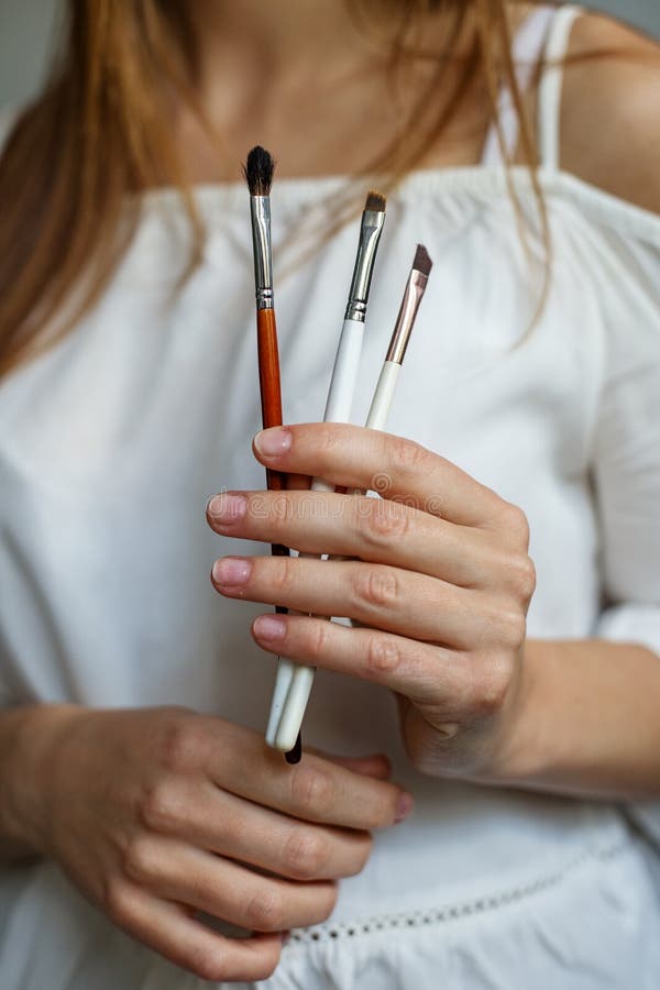 A woman holds several makeup brushes in her hands, a professional makeup artist stock images