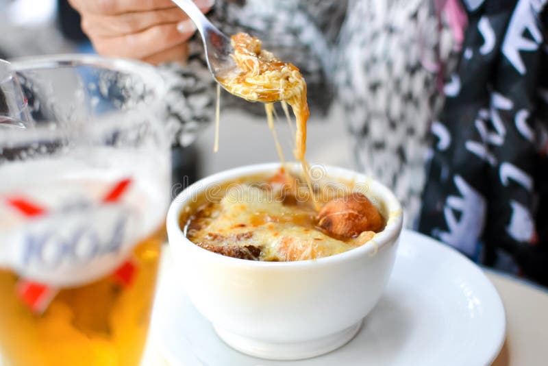 A woman holds a spoon over a delicious bowl of French onion soup at an outdoor cafe in Paris France royalty free stock photo A woman holds a spoon over a delicious bowl of French onion soup at an outdoor cafe in Paris France royalty free stock photo