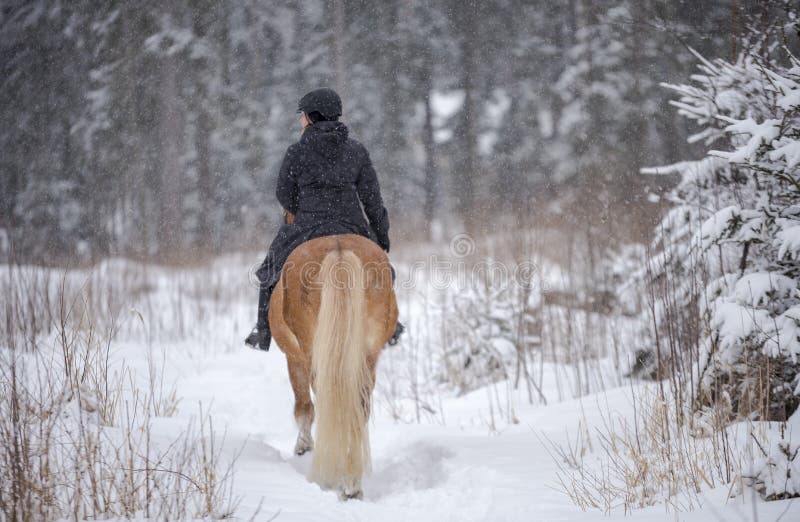 Woman horseback riding in winter snowfall