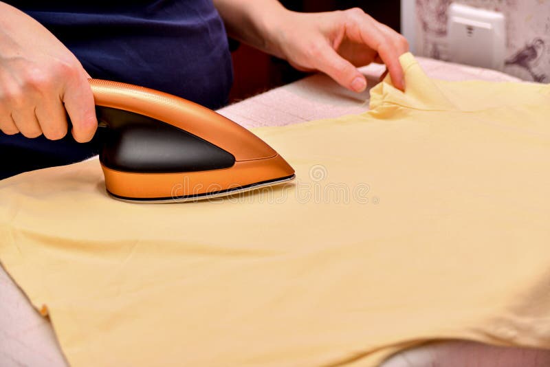 A Woman Irons Clothes after Washing with a Small Iron Stock Photo