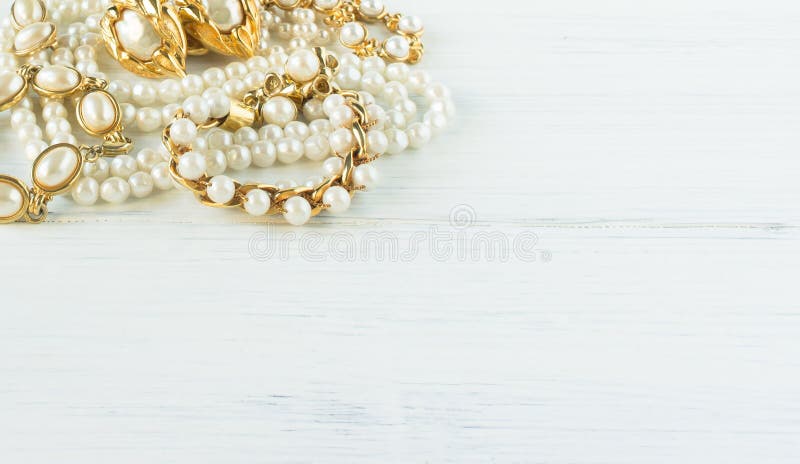 Woman Jewelry. Vintage jewelry background. Beautiful gold and pearl necklaces, bracelets and earrings on white wood. Flat lay