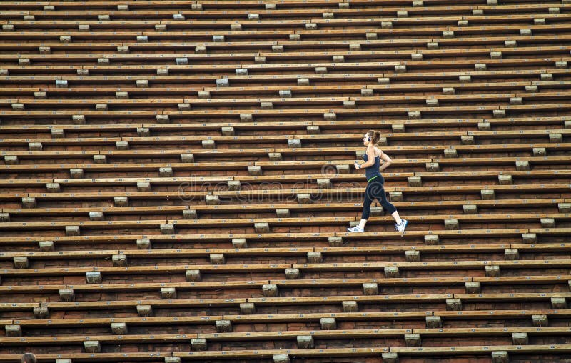 Woman jogging across bleacher seating Red Rocks Amphitheater in Morrison Colorado