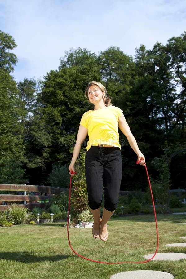 Pretty woman jumping rope in the garden