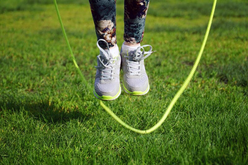 woman jumping on a skipping rope in a park close-up. woman jumping on a skipping rope in a park close-up.