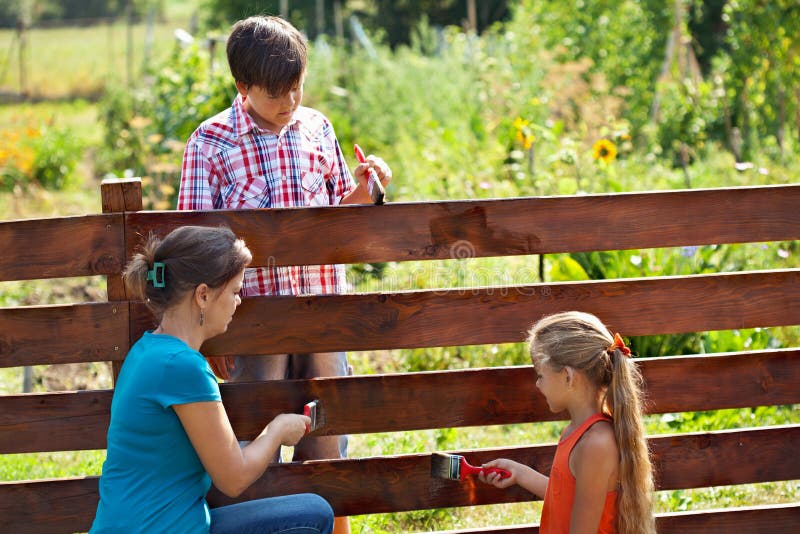 Woman and kids painting the garden fence royalty free stock images Woman and kids painting the garden fence royalty free stock images