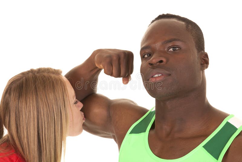 A men flexing his bicep and a women kissing the big muscle. A men flexing his bicep and a women kissing the big muscle.