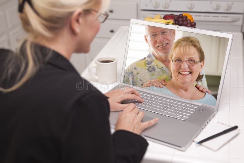 Woman In Kitchen Using Laptop - Online with Senior Couple