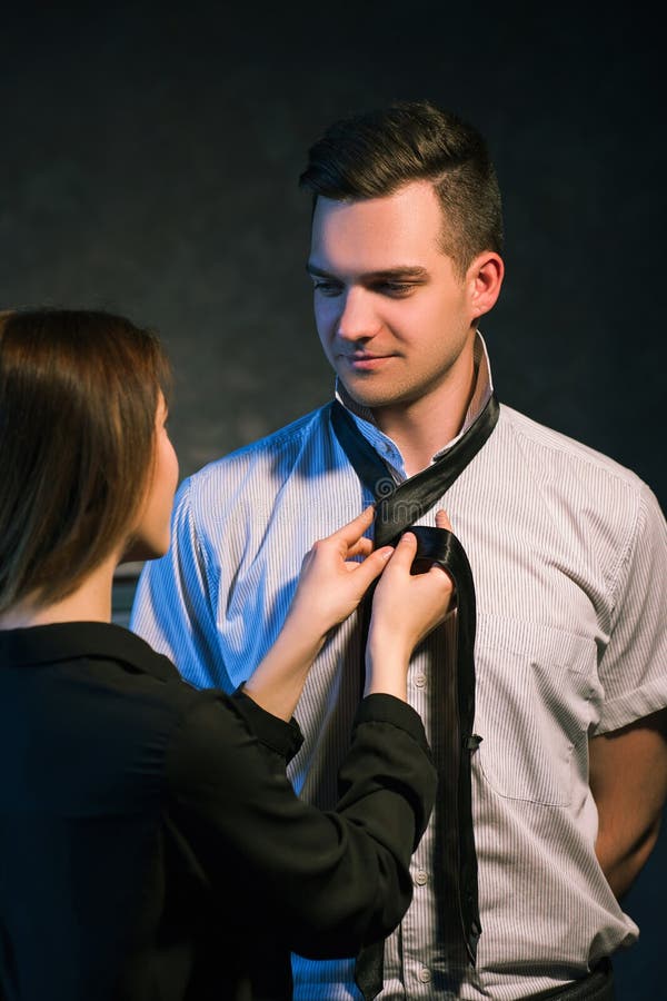 Woman knotting a tie on her boyfriend or husband. Couple family relationship. Love care help support concept. Woman knotting a tie on her boyfriend or husband. Couple family relationship. Love care help support concept