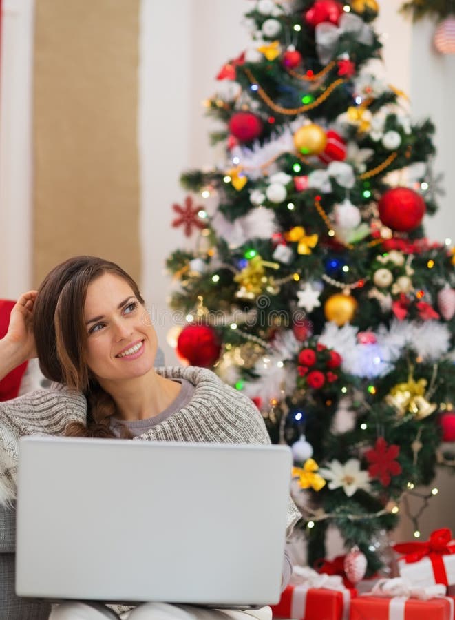 Woman with laptop sitting near Christmas tree