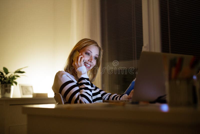 Woman with laptop and smartphone, making phone call.