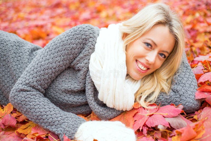 Woman laying in red leafs and smiling