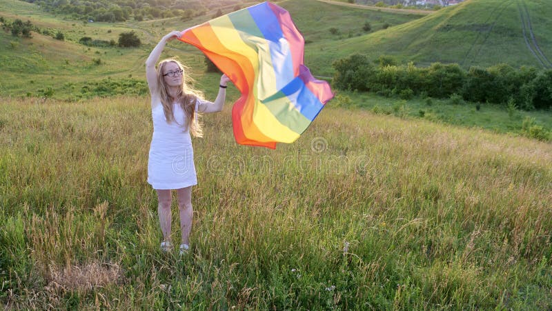 Woman lesbian with LGBT flag on a green field royalty free stock photography