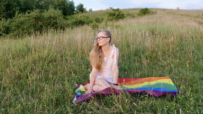 Woman lesbian with LGBT flag on a green field stock images