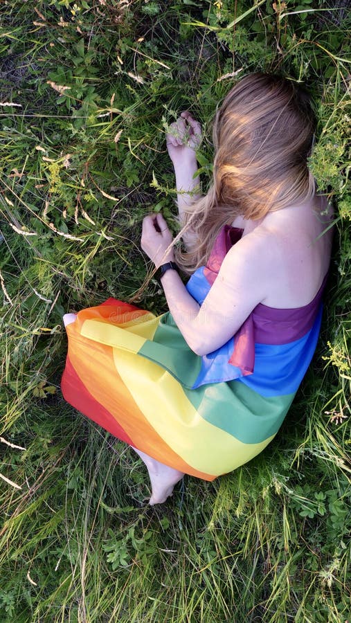 Woman lesbian with LGBT flag on a green field stock photo