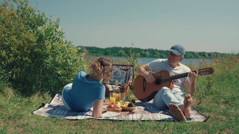 A woman listens to a man playing the guitar.