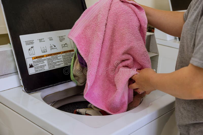 Woman Loading Towel in Washing Machine in the Laundry Stock Photo