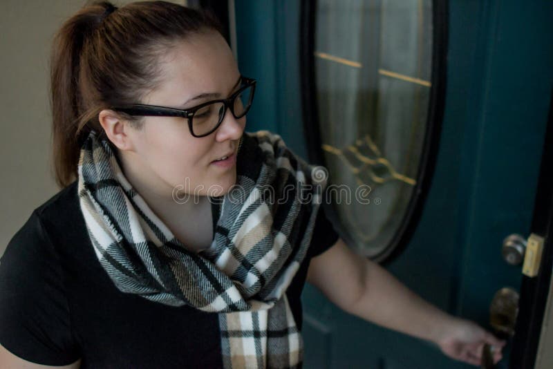 A woman locks her front door as she leaves home with a duffel bag over one arm. stock image A woman locks her front door as she leaves home with a duffel bag over one arm. stock image
